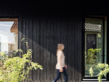 Lady walking past building with PermaChar timber cladding - charred timer cladding - Shou sugi ban wood cladding