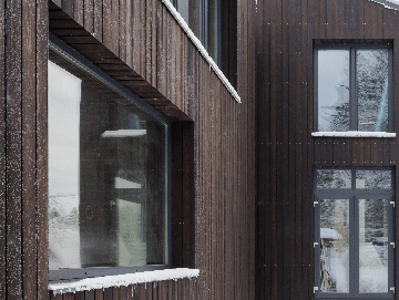 Building in the snow with charred timber cladding - PermaChar treatment - charred level: dusk