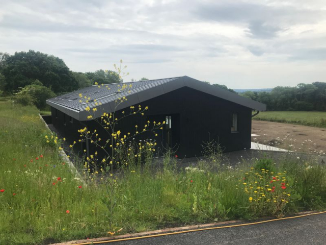 Charred timber clad building in wild flower meadow